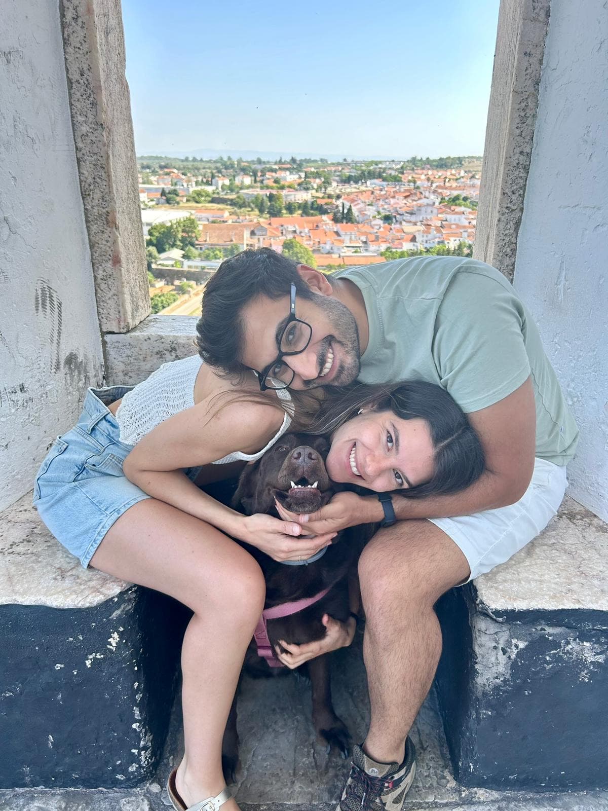 Sofia, Rodrigo e a Sweet sentados numa janela com a cidade ao fundo
